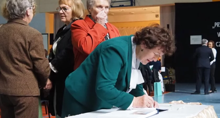 Na zdjęciu absolwentki szkoły, które wpisują się do księgi pamiątkowej