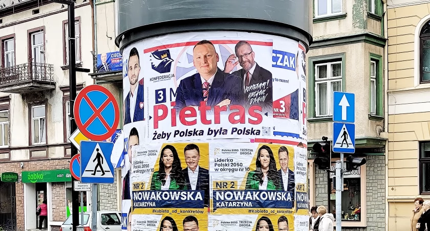 Na zdjęciu l Bus z plakatem promującym plakaty wyborcze kandydatów na słupie ogłoszeniowym  w centrum