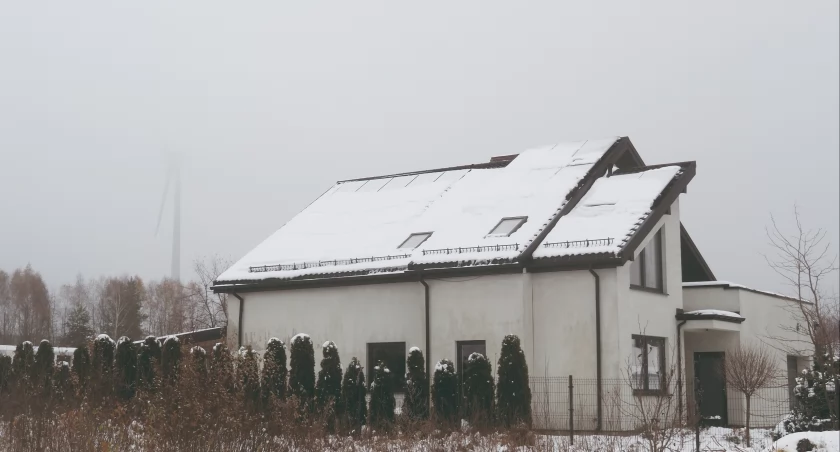 Na zdjęciu dom na osiedlu w miejscowości Malutkie z wiatrakiem w tle