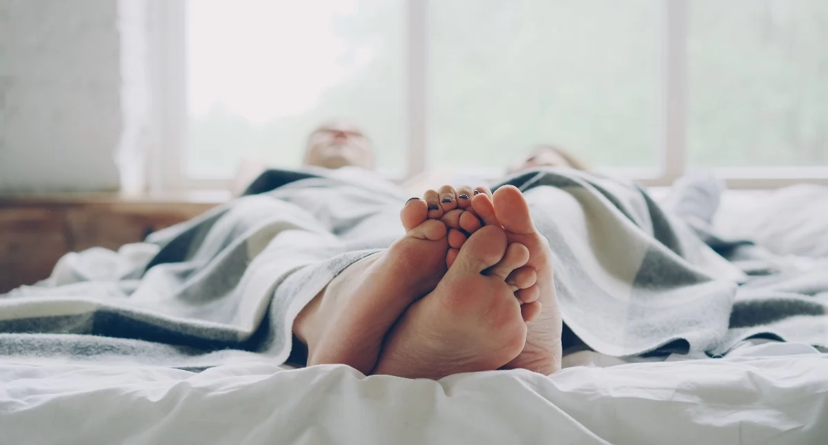 Na zdjęciu para w łóżku, fot. Pexels